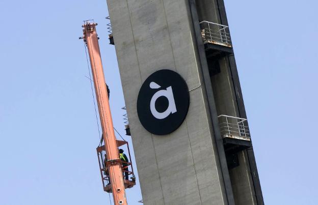 Operarios tras colocar el nuevo logotipo de la cadena autonómica. 