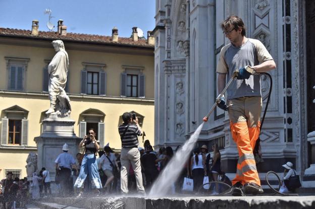 Un operario de limpieza baldea la calle en Florencia. 