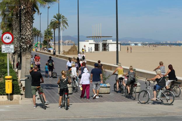 Un grupo de ciclistas accede al paseo marítimo junto a una señal que prohíbe circular en bici, ayer 