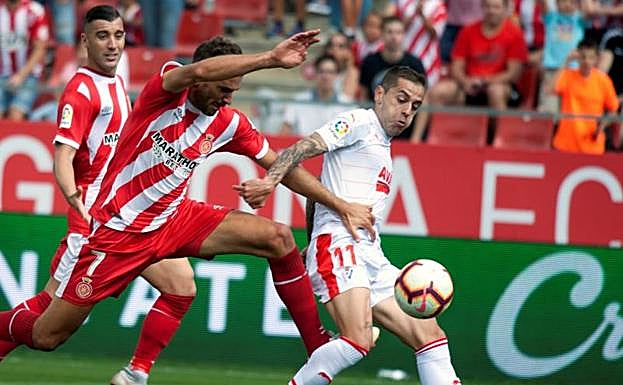 El delantero uruguayo del Girona Christian Stuani (i) disputa el balón con el centrocampista del Eibar, Rubén Peña.