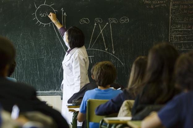 Una profesora, en un centro educativo con varios escolares 