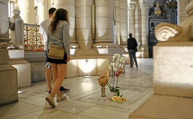 Una pareja pasea por la cripta de la catedral de la Almudena, al lado de la tumba de los Franco, con algunas flores.