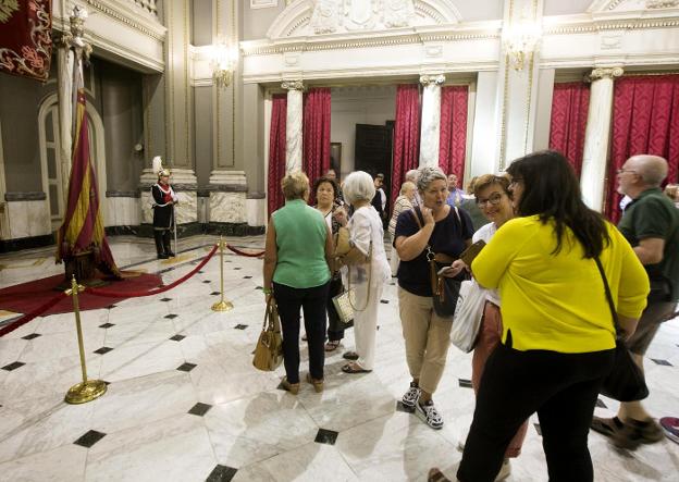 Decena de visitantes observan la Real Senyera, ayer por la mañana, en el Salón de Cristal. 