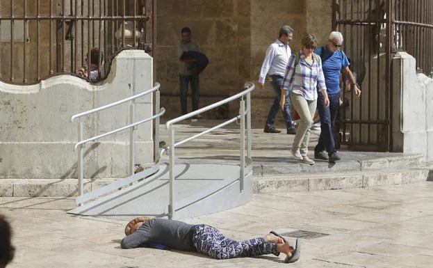 Una mujer, tumbada a la entrada de la Catedral. 