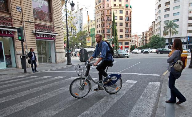 Un hombre cruza un paso de peatones de la calle Ruzafa subido en su bicicleta, en una imagen reciente. 