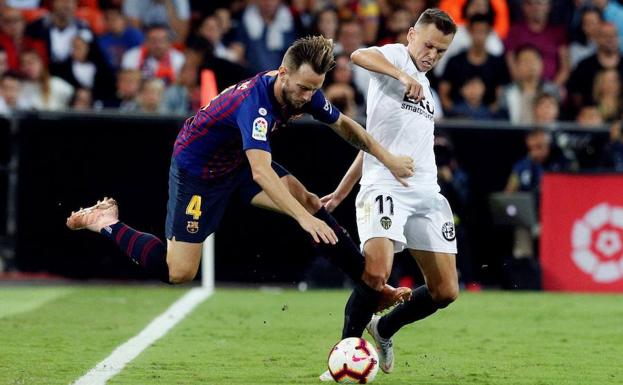 El delantero ruso del Valencia CF Denís Chéryshev (d) lucha con el croata Ivan Rakitic, del FC Barcelona, durante el partido de la octava jornada de Liga en Mestalla.