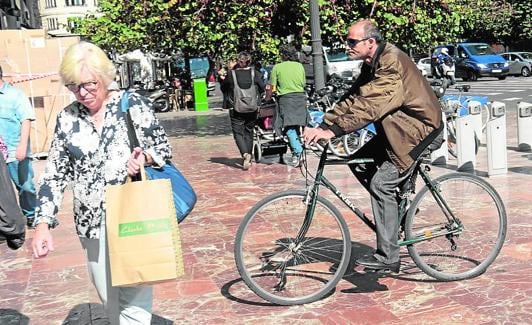 Por la acera. Un ciclista atraviesa una cera antes de entrar en una calle peatonal en el centro. 