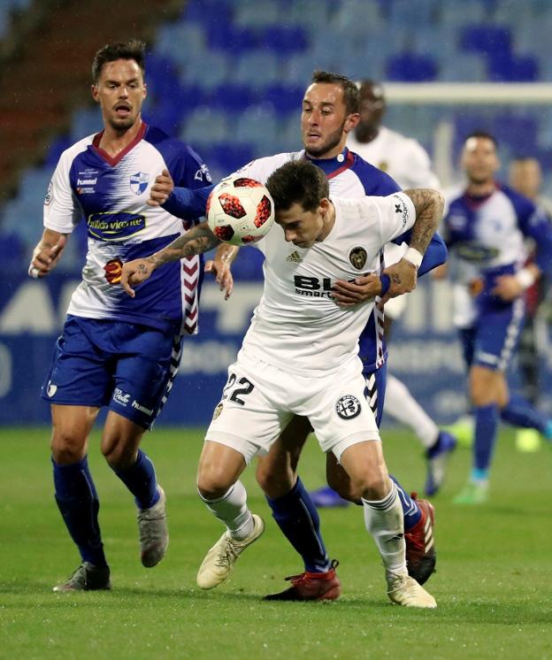 Santi Mina se lleva el balón con la cabeza pese a la presión de un rival. 