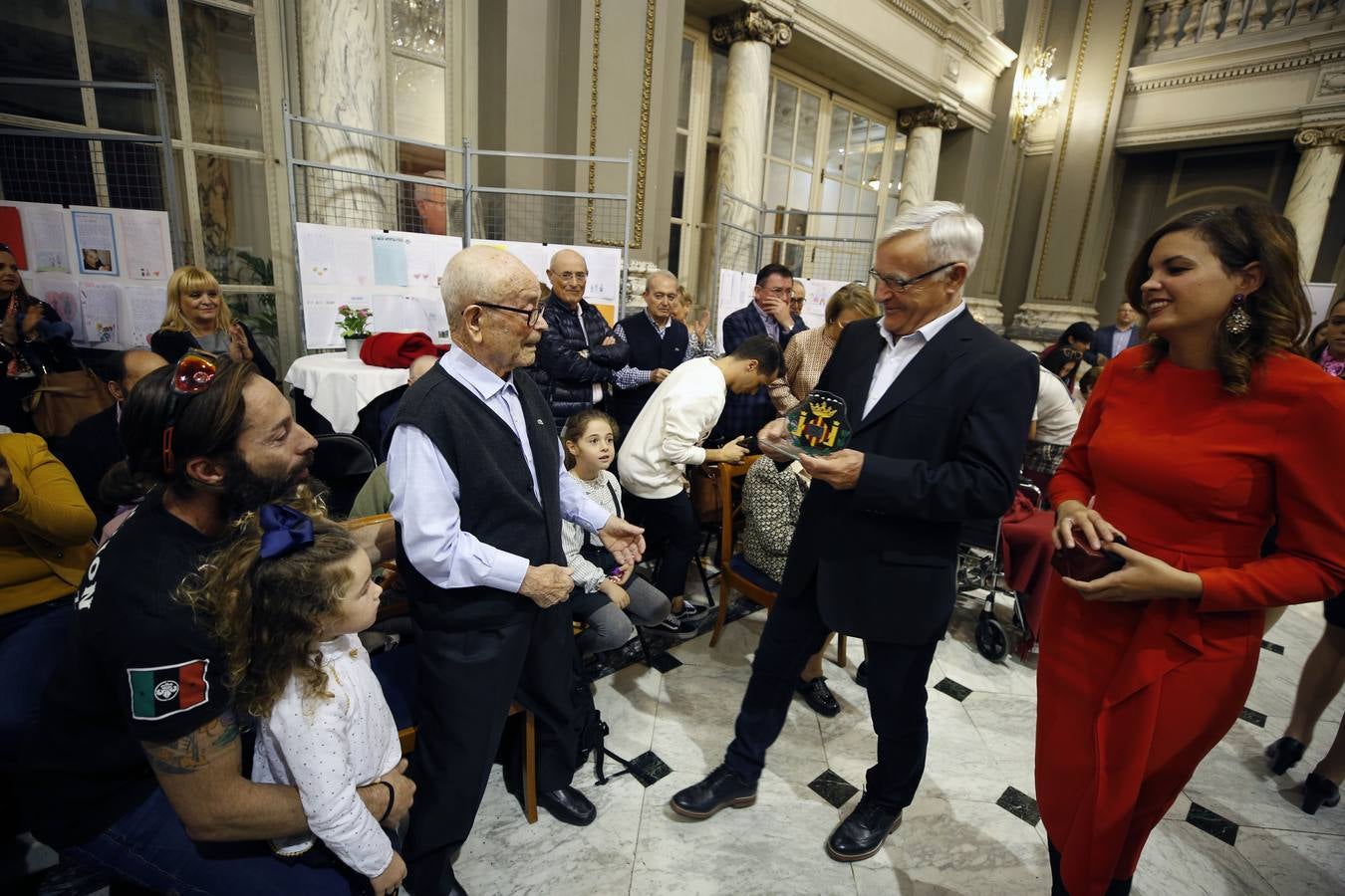 Una veintena de valencianos centenarios han acudido al Ayuntamiento para recibir un homenaje por haber alcanzado esa edad. Arropados por familiares y gracias a su apoyo, estos 21 vecinos de la ciudad han podido subir hasta el Salón de Cristal, para asistir al acto enmarcado en la Semana del Mayor de Valencia. 