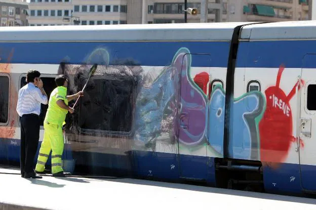 Un operario limpia el exterior de un tren atacado por los grafiteros en Alicante. 