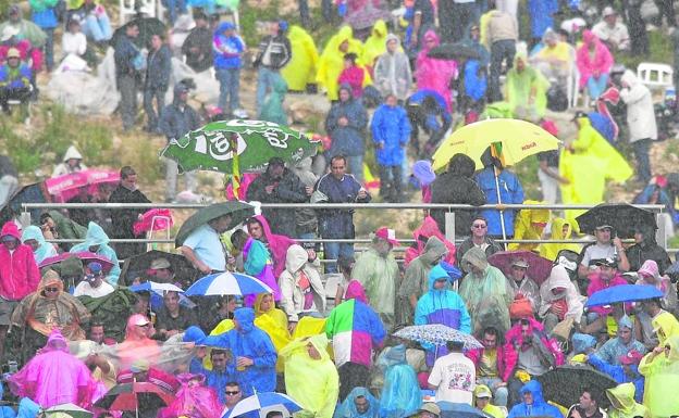 2001. Los aficionados se protegen como pueden bajo el aguacero.