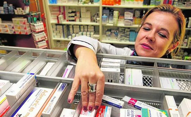Una farmacéutica busca un medicamento en su establecimiento. 
