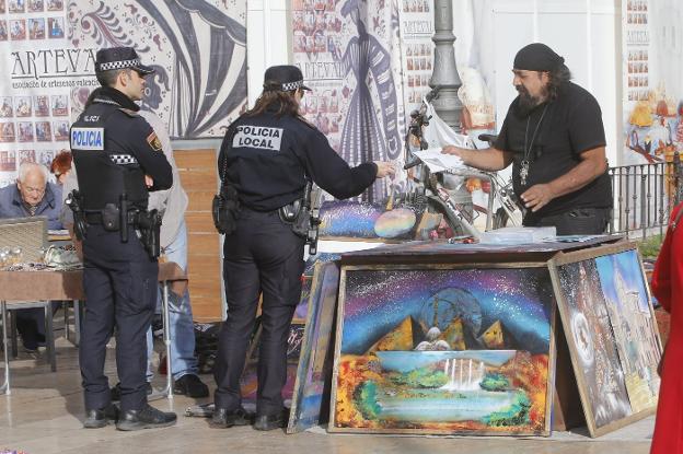 Dos agentes de la Policía Local solicitan la autorización a un vendedor, ayer. 