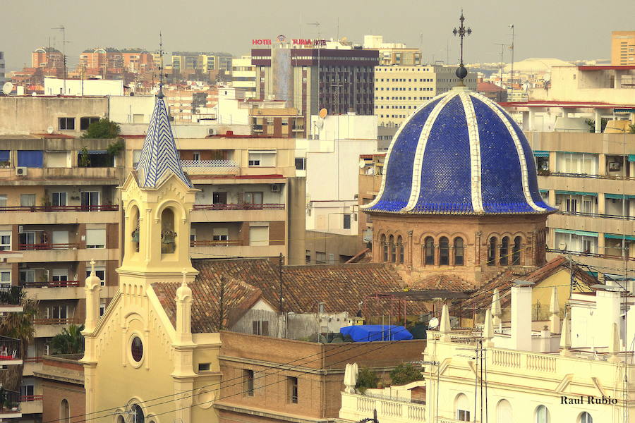 Valencia nunca deja de sorprender. Es habitual la imagen desde la calle de los múltiples campanarios que se encuentran en la ciudad. En el centro histórico aún encontramos más torreones eclesiásticos. Pero, ¿cómo se ve la ciudad desde el cobijo de las campanas?. Raúl Rubio, de la Associació de Mestres Campaners, ha inmortalizado esa visión de la que poca gente puede disfrutar: Valencia desde sus campanarios. Ver la plaza de San Agustín con una perspectiva diferente, contemplar el centro de la ciudad desde Santa Catalina, admirar Valencia desde las campanas del Real Monasterio de la Santísima Trinidad son algunos de las panorámicas exquisitas casi exclusivas para campaneros. La ciudad se redescubre desde las alturas, desde la perspectiva de gárgolas, campanas y tejados. Así es Valencia desde sus campanarios.