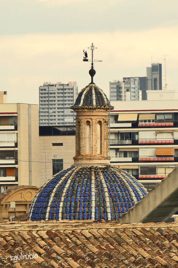 Valencia nunca deja de sorprender. Es habitual la imagen desde la calle de los múltiples campanarios que se encuentran en la ciudad. En el centro histórico aún encontramos más torreones eclesiásticos. Pero, ¿cómo se ve la ciudad desde el cobijo de las campanas?. Raúl Rubio, de la Associació de Mestres Campaners, ha inmortalizado esa visión de la que poca gente puede disfrutar: Valencia desde sus campanarios. Ver la plaza de San Agustín con una perspectiva diferente, contemplar el centro de la ciudad desde Santa Catalina, admirar Valencia desde las campanas del Real Monasterio de la Santísima Trinidad son algunos de las panorámicas exquisitas casi exclusivas para campaneros. La ciudad se redescubre desde las alturas, desde la perspectiva de gárgolas, campanas y tejados. Así es Valencia desde sus campanarios.