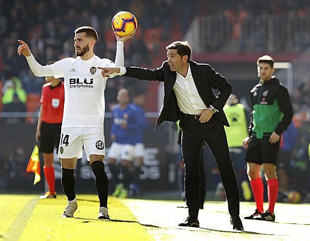 Marcelino da instrucciones a sus jugadores mientras que Gayà saca de banda. 