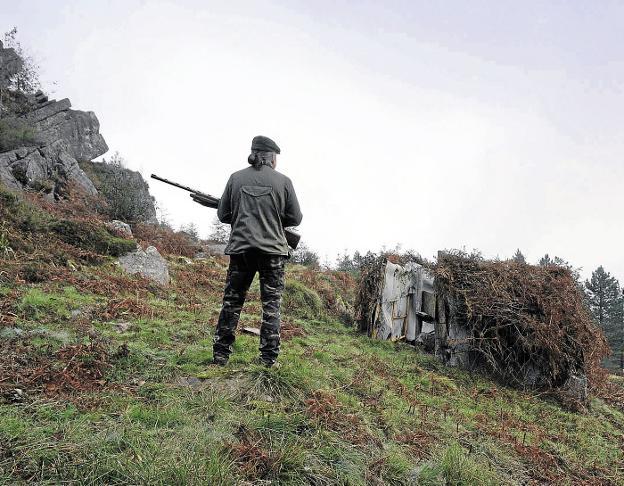 Un cazador otea un paraje mientras sostiene su escopeta. 