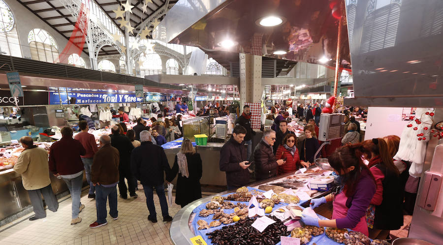 Lleno hasta la bandera. Así ha estado este sábado el centro de Valencia con curiosos que querían fotografiar todos los escaparates, pero sobre todo con gente haciendo las compras de Nochevieja. Uno de los puntos de encuentro que ha registrado el cartel de 'completo' ha sido una vez más el Mercado Central. El marisco, salazones, frutos secos y quesos variados llenan las cestas a dos días del Fin de Año. 