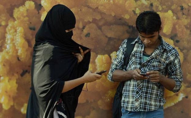 Una mujer india mira su teléfono móvil mientras camina por una calle en Nueva Delhi. 