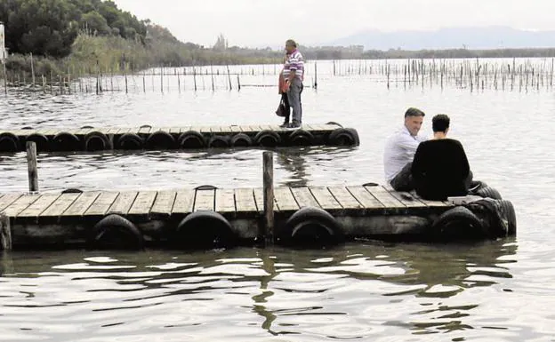 Varias personas, en uno de los muelles de la Albufera. 