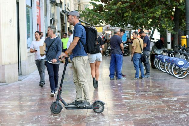 Un usuario de patinete recorre la acera en la plaza del Ayuntamiento, en una imagen de archivo. 