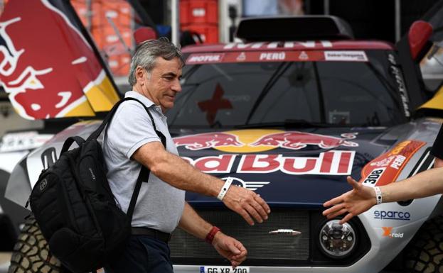 Carlos Sainz saluda a un miembro de su equipo delante del coche con el que competirá en el Dakar.