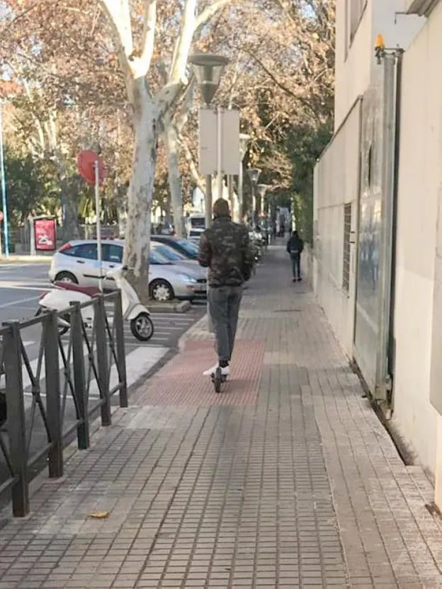 Un joven circula con un patinete eléctrico por una acera en Xàtiva. 