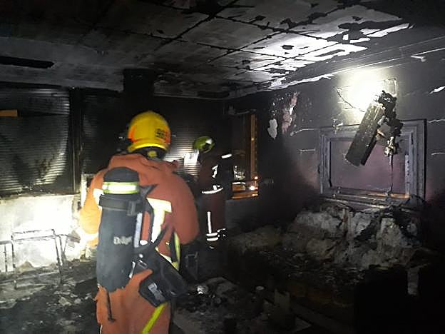 Dos bomberos inspeccionan la vivienda de la Pobla de Farnals afectada por el fuego. 