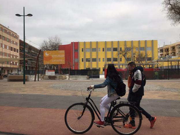 Unos vecinos del distrito de Corea pasan por delante del colegio Cervantes de Gandia, aún en obras. 