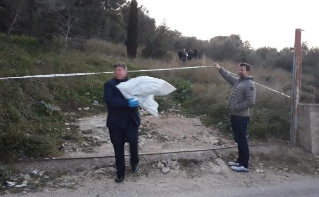 Un investigador traslada una bolsa con restos humanos encontrados cerca del Hospital de la Ribera.
