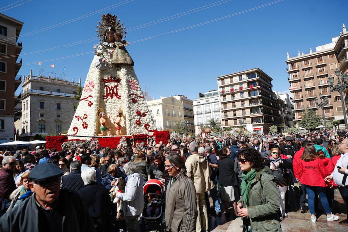 La Ofrenda concluyó este lunes después de que miles de falleros desfilaran para llevar las flores a la Virgen de los Desamparados. Este martes, a la luz del día se ha desvelado ante los ojos de los valencianos el aspecto definitivo del manto de la 'Geperudeta'. Claveles blancos, rojos y rosas componen componen el diseño del vestidor Rafael Chordá. Un floreado manto con el blanco como color predominante y que preside estos días la plaza de la Virgen, ante su basílica.