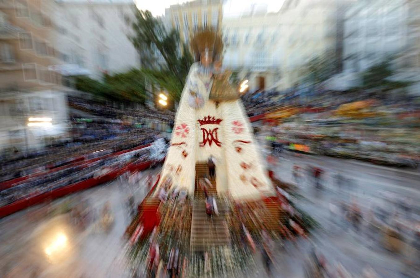 La Ofrenda concluyó este lunes después de que miles de falleros desfilaran para llevar las flores a la Virgen de los Desamparados. Este martes, a la luz del día se ha desvelado ante los ojos de los valencianos el aspecto definitivo del manto de la 'Geperudeta'. Claveles blancos, rojos y rosas componen componen el diseño del vestidor Rafael Chordá. Un floreado manto con el blanco como color predominante y que preside estos días la plaza de la Virgen, ante su basílica.