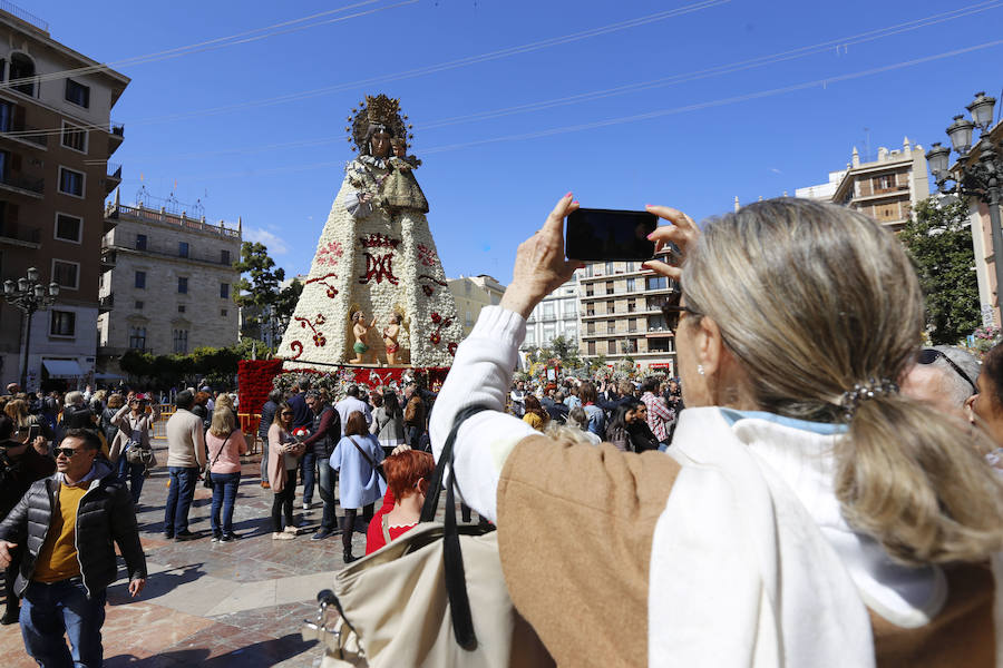 La Ofrenda concluyó este lunes después de que miles de falleros desfilaran para llevar las flores a la Virgen de los Desamparados. Este martes, a la luz del día se ha desvelado ante los ojos de los valencianos el aspecto definitivo del manto de la 'Geperudeta'. Claveles blancos, rojos y rosas componen componen el diseño del vestidor Rafael Chordá. Un floreado manto con el blanco como color predominante y que preside estos días la plaza de la Virgen, ante su basílica.