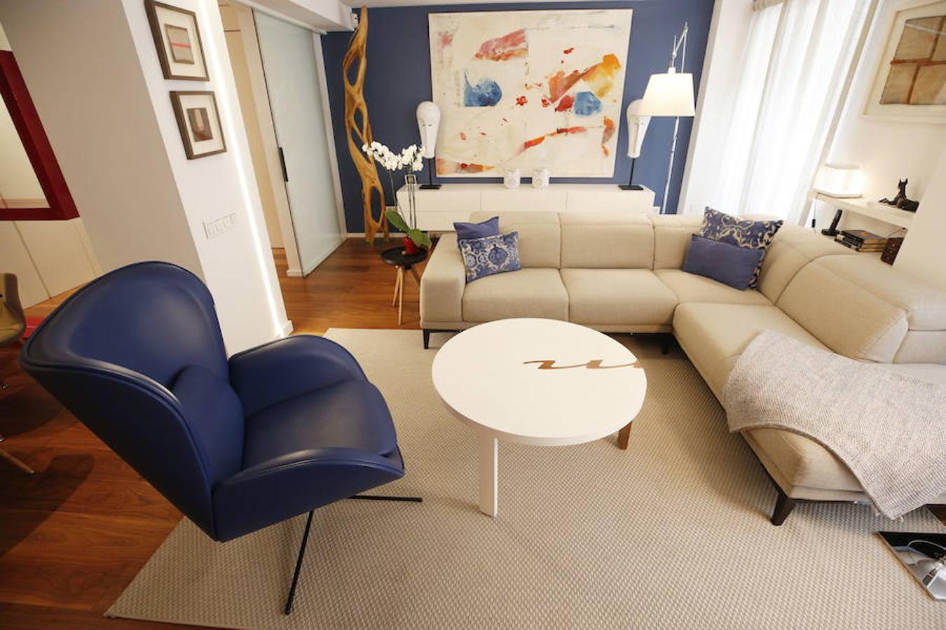 Las peticiones que Mariche Correcher planteó a la diseñadora creativa Carmen Bayarri estaban muy claras: que la casa tuviera muchos armarios, que la cocina y el salón estuviesen unidos pero a la vez se pudieran independizar y que la zona más tranquila de la casa albergara una suerte de suite en la que poder refugiarse después de la jornada de trabajo. Además le pidió que al entrar a la vivienda pudiera ver un ramo de flores. Con estas premisas, hace cuatro años se esbozó el proyecto en esta casa ubicada en una finca con carácter en pleno Ensanche valenciano. Para vestir el suelo escogieron madera de nogal, al igual que en las puertas que dividen las estancias. El resto de las puertas son blancas con las manivelas en negro y van de suelo a techo buscando potenciar la sensación de amplitud. En los baños instalaron porcelánico negro en el suelo que contrasta muy bien con el nogal. Carmen propuso ubicar junto a la entrada una escultura lacada flotante en rojo Ferrari que enmarca el espacio y permite ver el ramo de flores que reposa sobre la mesa del salón nada más entrar, que era uno de los deseos de la propietaria. La iluminación está integrada en la propia arquitectura. En lugar de obviar los pilares se decidió marcarlos de manera interna con filas de luz para ofrecer un ambiente casi escultórico. 