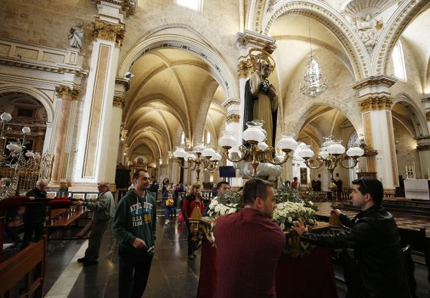 Varias personas sitúan una de las imágenes de San Vicente Ferrer en los pasillos de la catedral. 