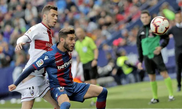 Rochina protege el balón ante la presión de un jugador del Huesca. 