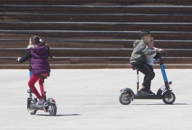 Tres niños circulan con patinetes eléctricos en un tramo del jardín del Turia. 