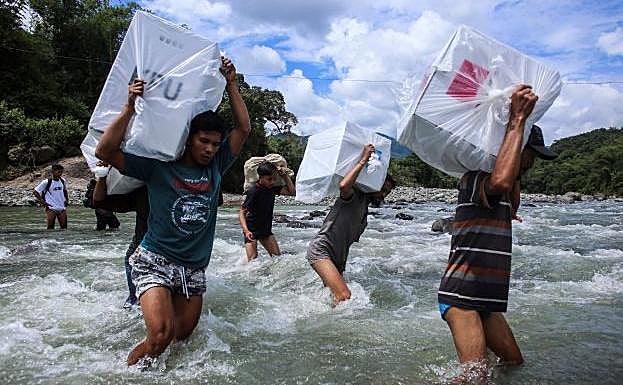 Los trabajadores cruzan un río para transportar las urnas a pueblos remotos.
