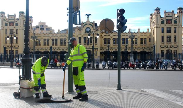 Dos operarios fumigan una alcantarilla en la calle Marqués de Sotelo. 