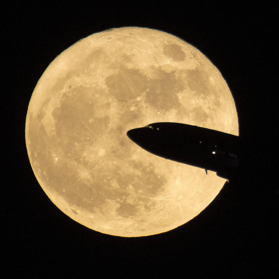 Un avión vuelva por delante de la superluna.