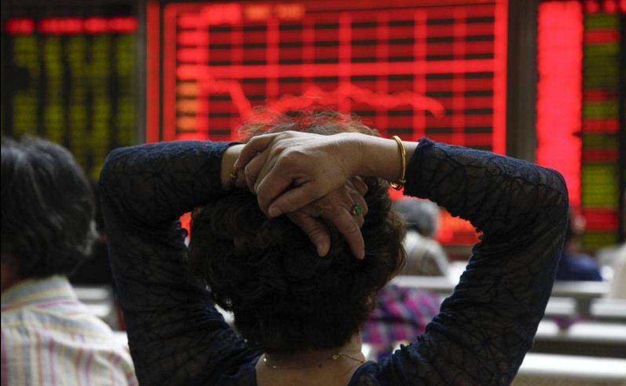 Una mujer comprueba la evolución de la bolsa de Shangái en Pekín.