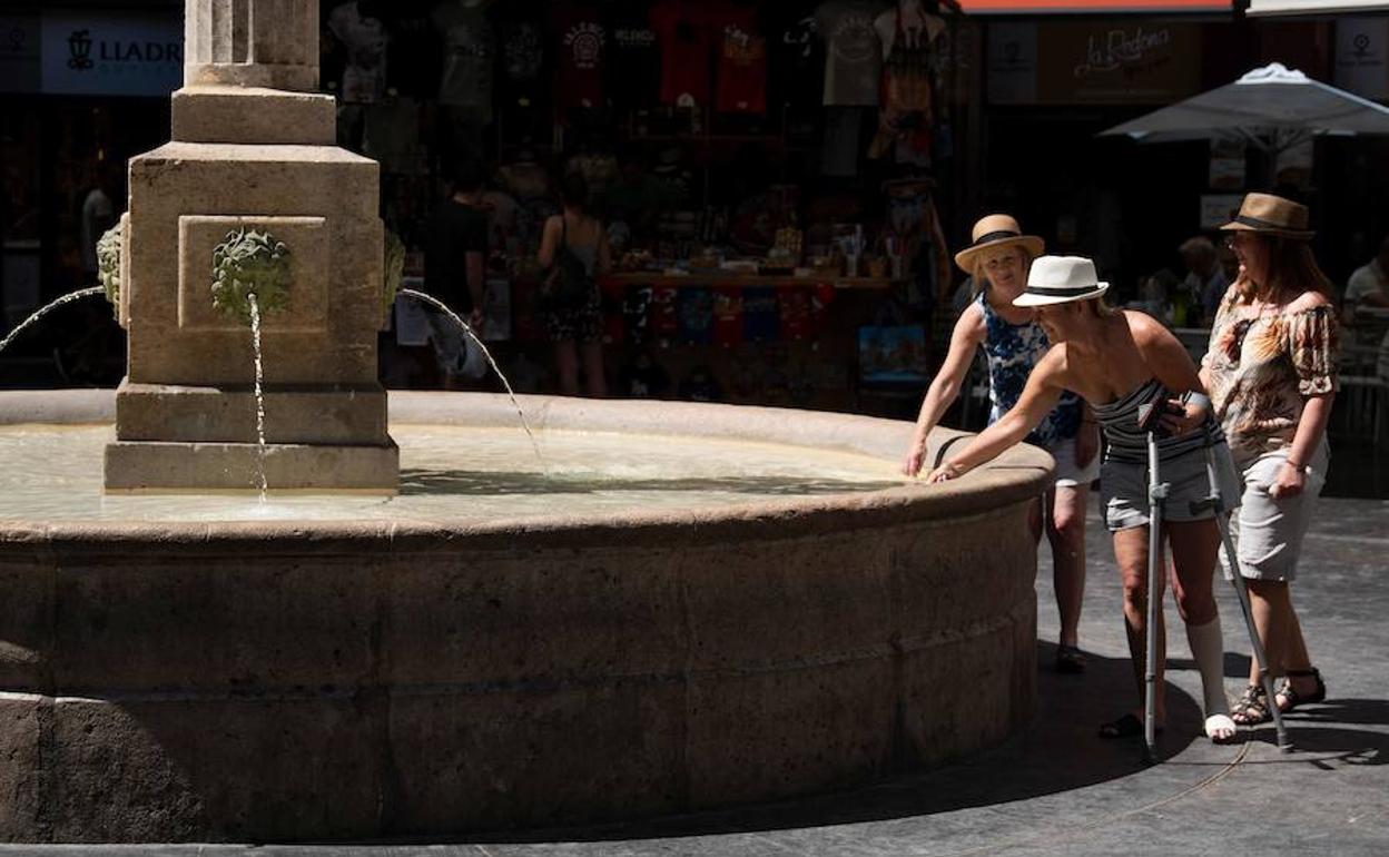 Tres turistas se refrescan en una fuente en Valencia. 