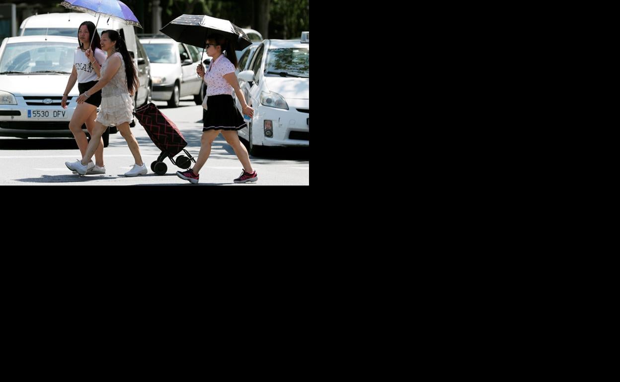 Tres mujeres se protegen del sol con sombrillas, este jueves en Valencia.