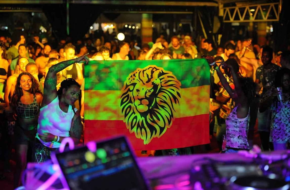 La 26 edición del certamen internacional reggae Rototom Sunsplash ha arrancado y ha convertido a la localidad castellonense en la capital mundial del reggae y en epicentro cultural, con dosis extra de compromiso medioambiental. La apuesta ofrece, hasta el próximo día 22, cien conciertos en siete escenarios por los que pasarán artistas de 23 nacionalidades. La cita, que cumple su primera década en España tras aterrizar desde Italia en el verano de 2010, trae ritmos que van desde el reggae, el dancehall o el dub, a la música de raíces negras, la música más profundos del Caribe, pasando por las sesiones de dj a ritmo de afrobeat y coupé-décalé. El festival recibirá a exponentes jamaicanos como el ganador del Grammy e hijo de Bob, Ziggy Marley o a la familia del reggae moderno: Morgan Heritage. También acudirán leyendas del reggae como el grupo The Abyssinians, -que cumple 50 años- entre otros.