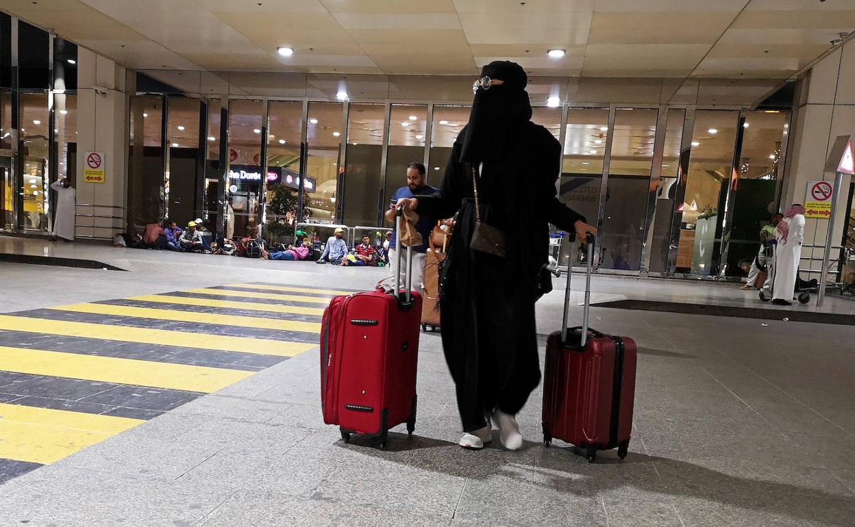 Una mujer saudita camina con su equipaje al llegar al Aeropuerto Internacional Rey Fahd en Dammam, Arabia Saudita.