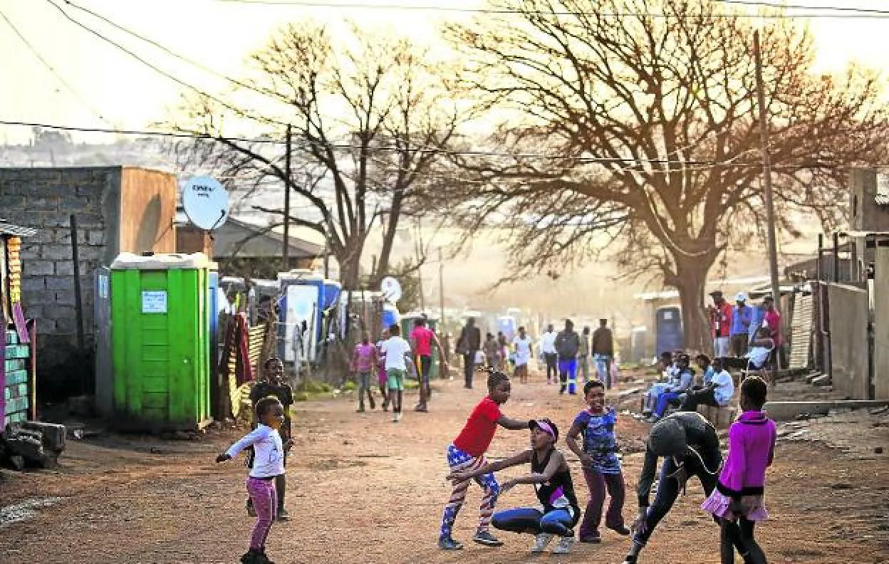 Niños juegan al atardecer en las calles de la barriada de Kliptown, en Soweto. :: Leila navidizumapress.com