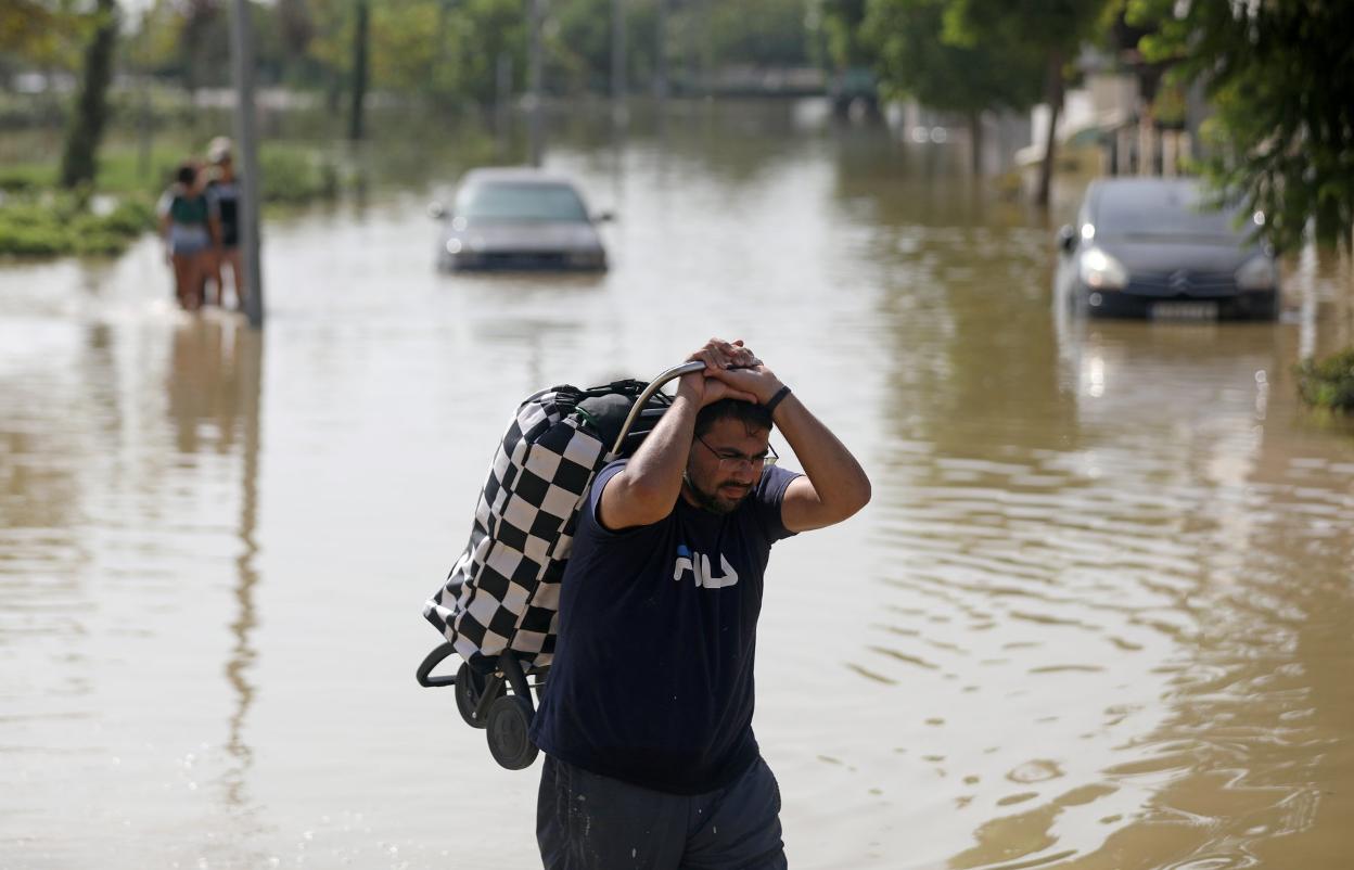  Un hombre cargado con un carro de compra cruza ayer una zona inundada en Dolores.