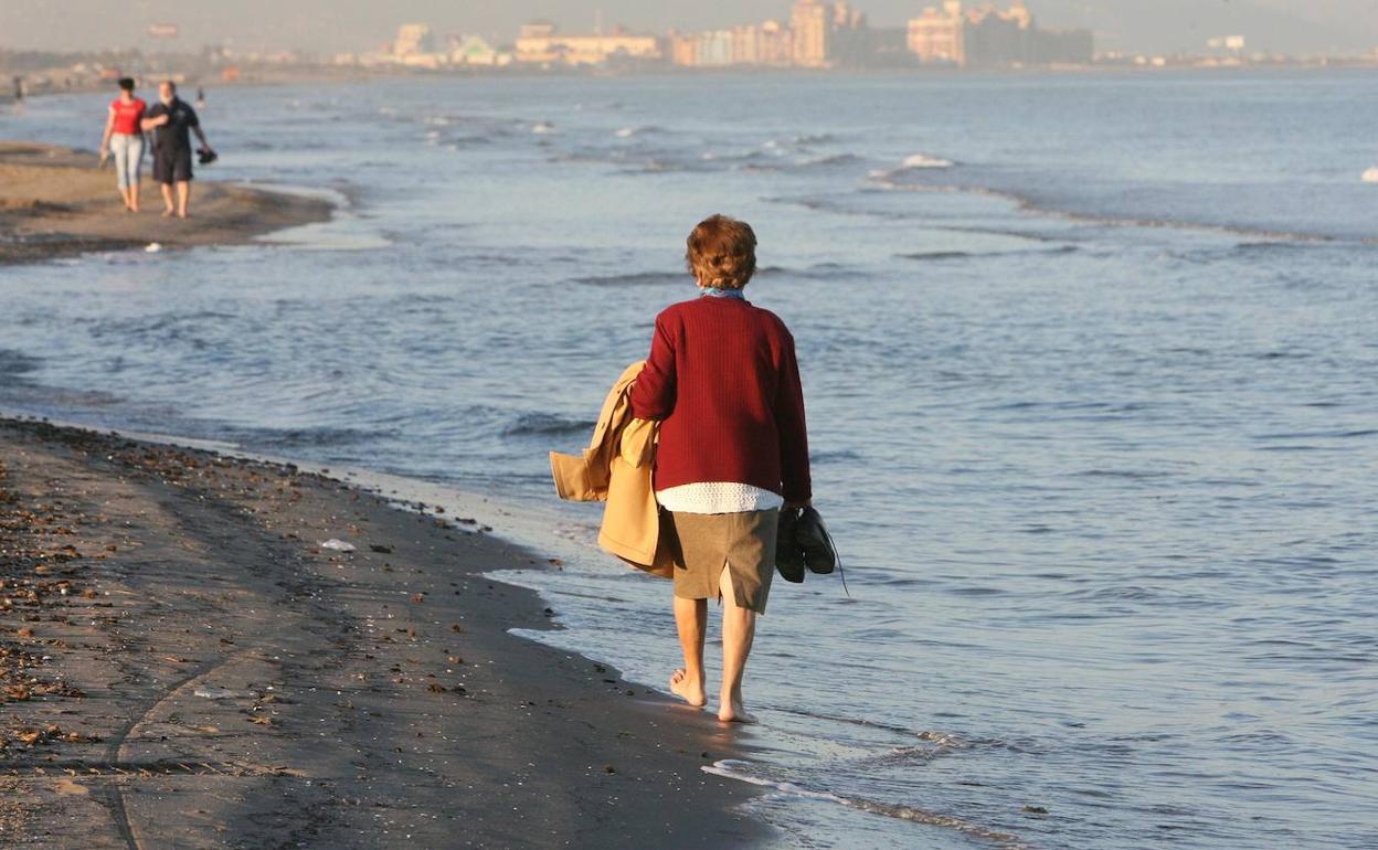 Una mujer pasea por la orilla de la playa de la Malvarrosa.