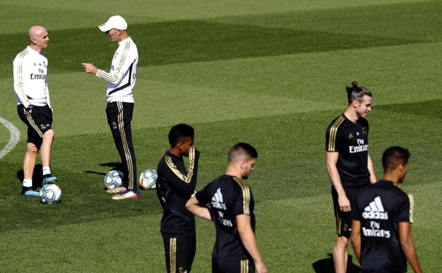 Zidane, con gorra, charla con su segundo, Davide Bettoni, mientras sus jugadores hacen un rondo