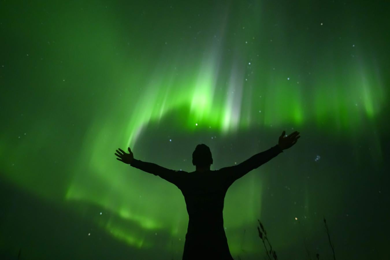 El surfista indonesio Edi Siswanto, saluda a la aurora boreal en Unstad, Islas Lofoten, más allá del Círculo Polar Ártico, el 27 de septiembre de 2019.